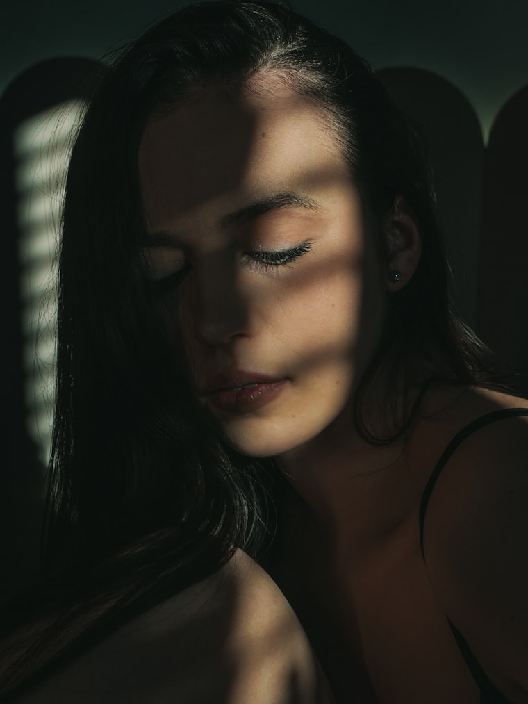 Mujer en luz baja, con la mirada baja, al final de la jornada