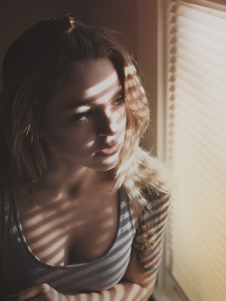 Sombras de una persiana sobre una persona junto a la ventana